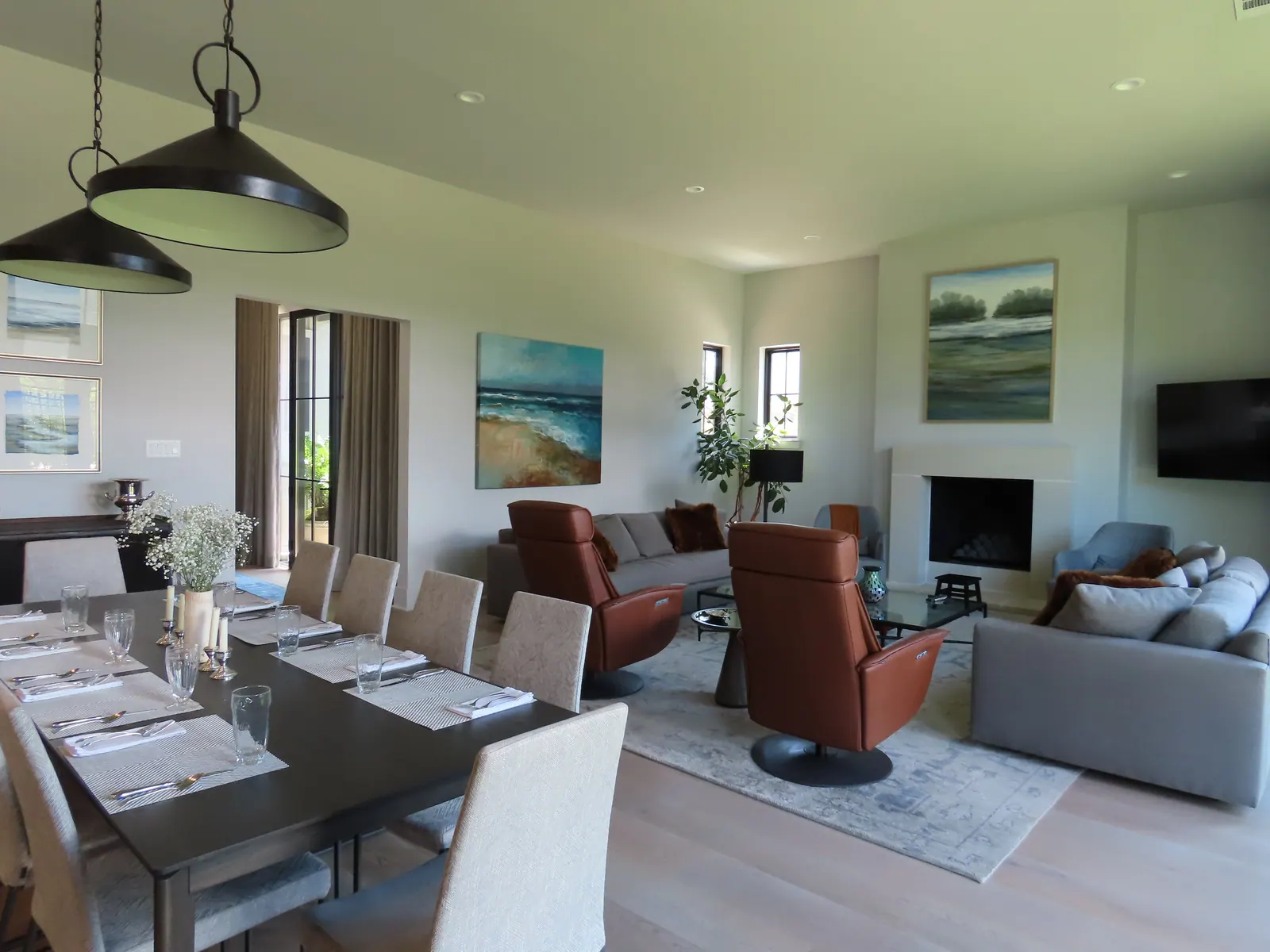 A light room with two leather armchairs, a grey sofa and a long dining table