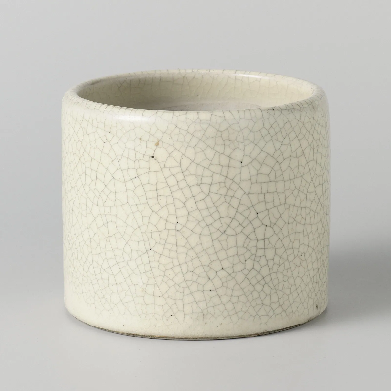 A cylindrical stoneware pot with a cream glaze